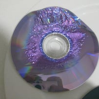 A broken cd on a white surface

AI-generated content may be incorrect.